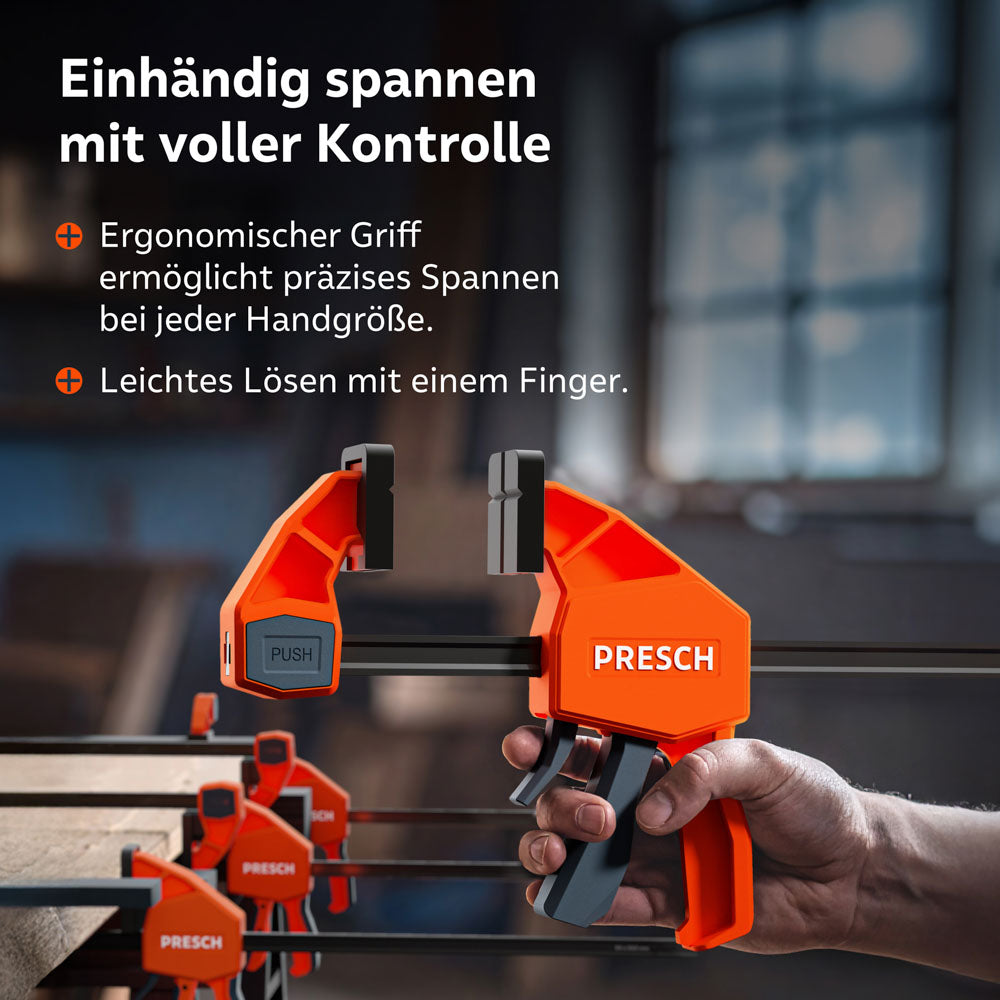 Nahaufnahme der kontrollierten Handhabung: Der ergonomische Griff der 150kg Zwinge erlaubt präzises Arbeiten bei jeder Handgröße. Ein kleiner Druckhebel ermöglicht das mühelose Lösen der Spannung mit nur einem Finger.