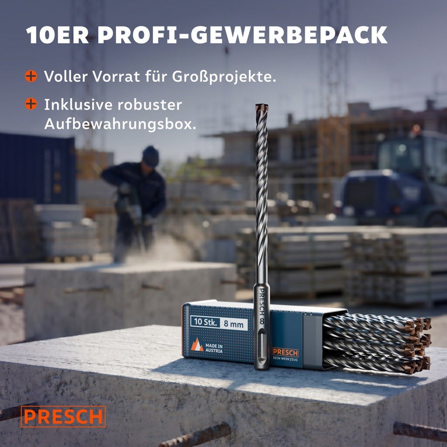 Ein SDS-Plus Hammerbohrer steht aufrecht auf der Aufbewahrungsbox für 10 Stück, im Hintergrund arbeitet ein Handwerker auf einer Großbaustelle