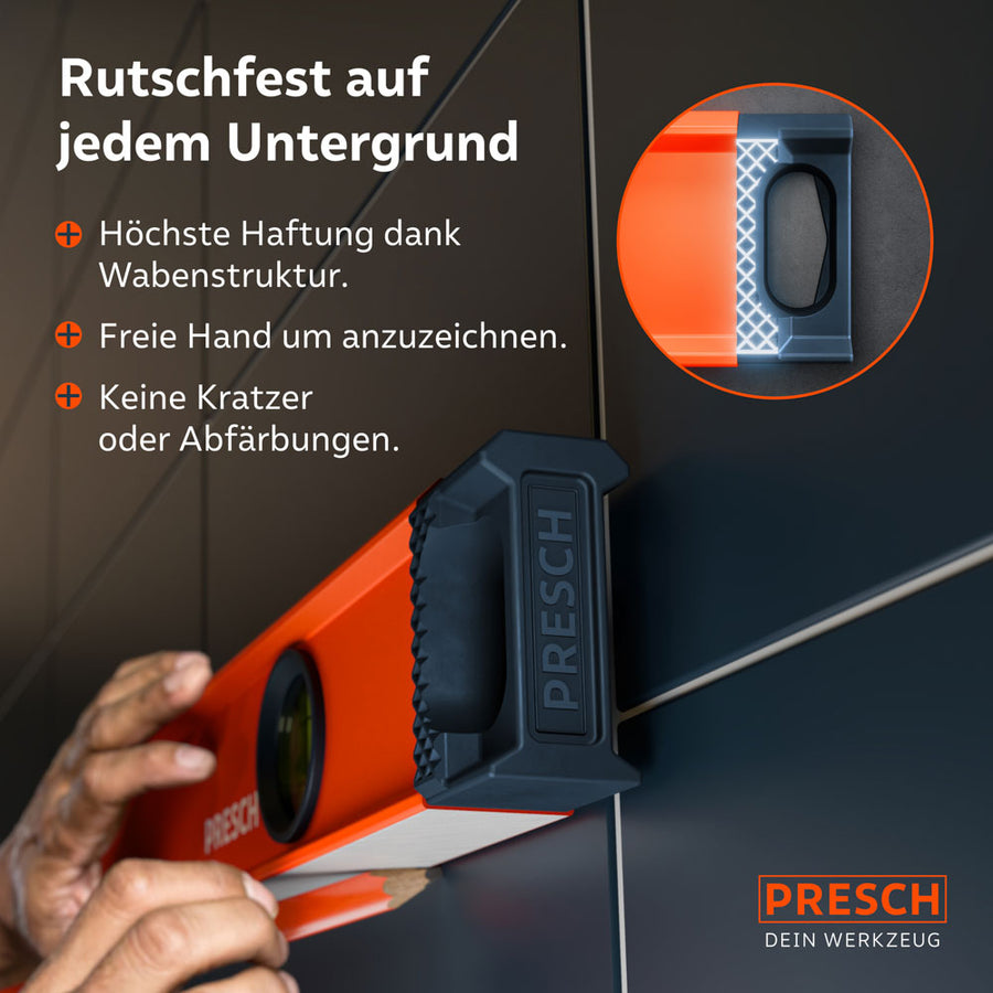 Die PRESCH Wasserwaage liegt fest an einer glatten Fliesenwand an; eine Vergrößerung zeigt die Wabenstruktur der Endkappen, die für höchste Haftung beim Anzeichnen sorgt, ohne Kratzer zu hinterlassen.
