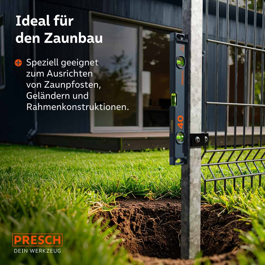Die magnetische PRESCH Wasserwaage (40cm) haftet selbstständig an einem verzinkten Metallpfosten beim Zaunbau; dies ermöglicht eine präzise, freihändige vertikale Ausrichtung des Pfostens vor dem Einbetonieren.