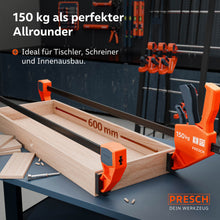 Anwendungsbeispiel bei langen Werkstücken: Zwei 600mm Einhandzwingen fixieren eine breite Holzkonstruktion auf einer Werkbank während des Verleimens; perfekt für Tischler und Schreiner.