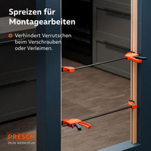 Montagebeispiel im Innenausbau: Zwei Zwingen werden im Spreizmodus eingesetzt, um eine Türzarge während des Einbaus stabil und exakt auf Distanz zu halten.