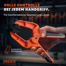 Hand bedient eine Federzwinge mit gummierten Griffzonen für komfortables Spannen und Lösen.