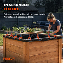 Federzwingen fixieren eine Teichfolie am Rand eines Hochbeets, während sie festgeklopft wird.