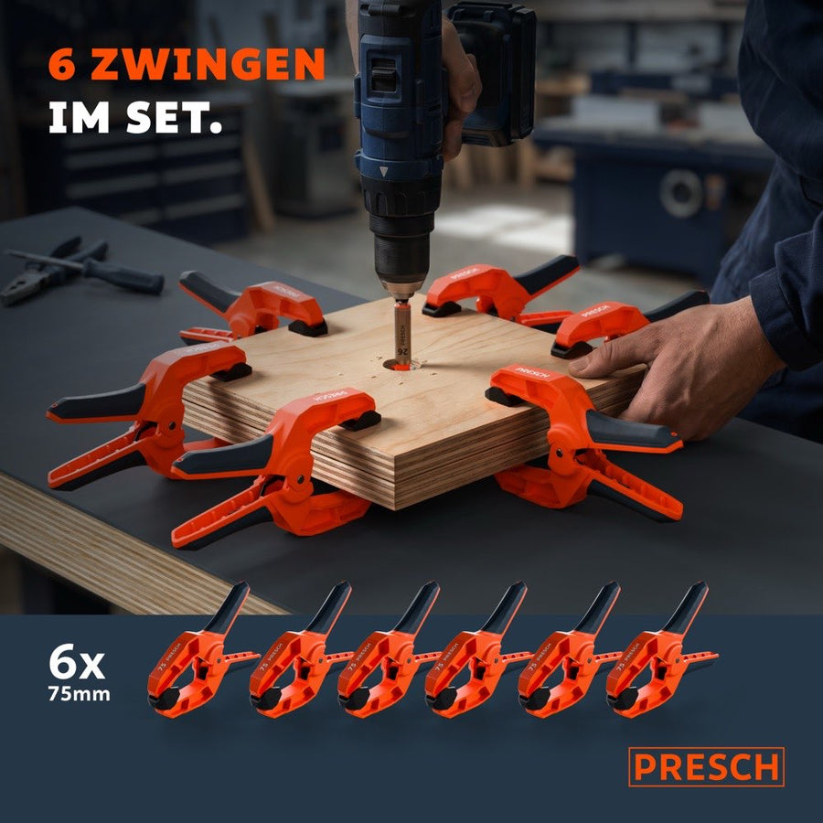 Sechs Federzwingen umschließen sternförmig ein Holzbrett, in dessen Mitte gerade gebohrt wird.