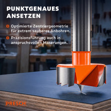 Zentrierspitze des Forstnerbohrers setzt punktgenau auf einer Spanplatte an.
