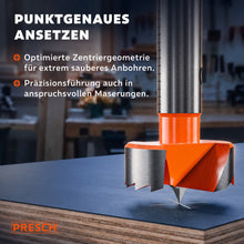 Zentrierspitze des Forstnerbohrers setzt punktgenau auf einer Spanplatte an.
