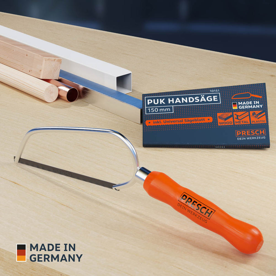 Présentation du produit de la scie PUK sur une surface en bois à côté de différents matériaux tels que des tuyaux en cuivre, du bois et des profilés en aluminium.