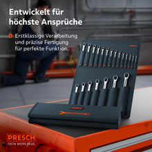 Le sac à roulettes avec le set professionnel de 21 pièces repose sur un chariot d'atelier. En arrière‑plan, un mécanicien travaille sur des installations industrielles, soulignant l'adéquation pour les travaux professionnels d'atelier et de montage.