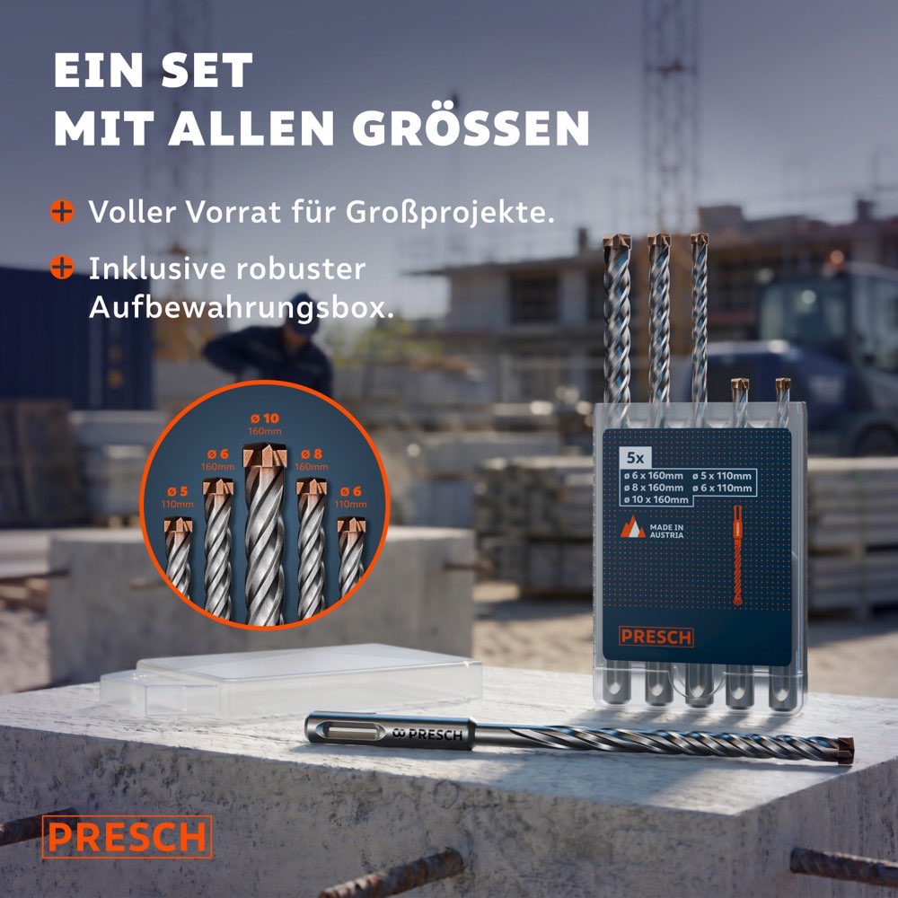 Fünf SDS-Plus Hammerbohrer in unterschiedlichen Längen stehen in der Aufbewahrungsbox auf einer Betonplatte, im Hintergrund eine aktive Großbaustelle