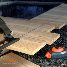 Préparation précise pour la construction en bois : une ligne tracée à la craie bleue sert de repère exact pour la découpe de longues planches de bois à la scie circulaire manuelle.