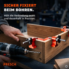 Handwerker bohrt mit dem Akkuschrauber, während Spannwinkel die Ecke eines Holzkastens halten
