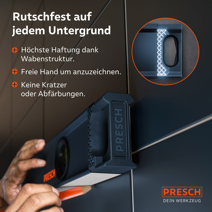 Die Wasserwaage liegt sicher an einer Wandfliese an; die Wabenstruktur der Endkappen sorgt für maximale Rutschfestigkeit beim Anzeichnen, ohne Abfärbungen oder Kratzer auf dem Untergrund zu hinterlassen.