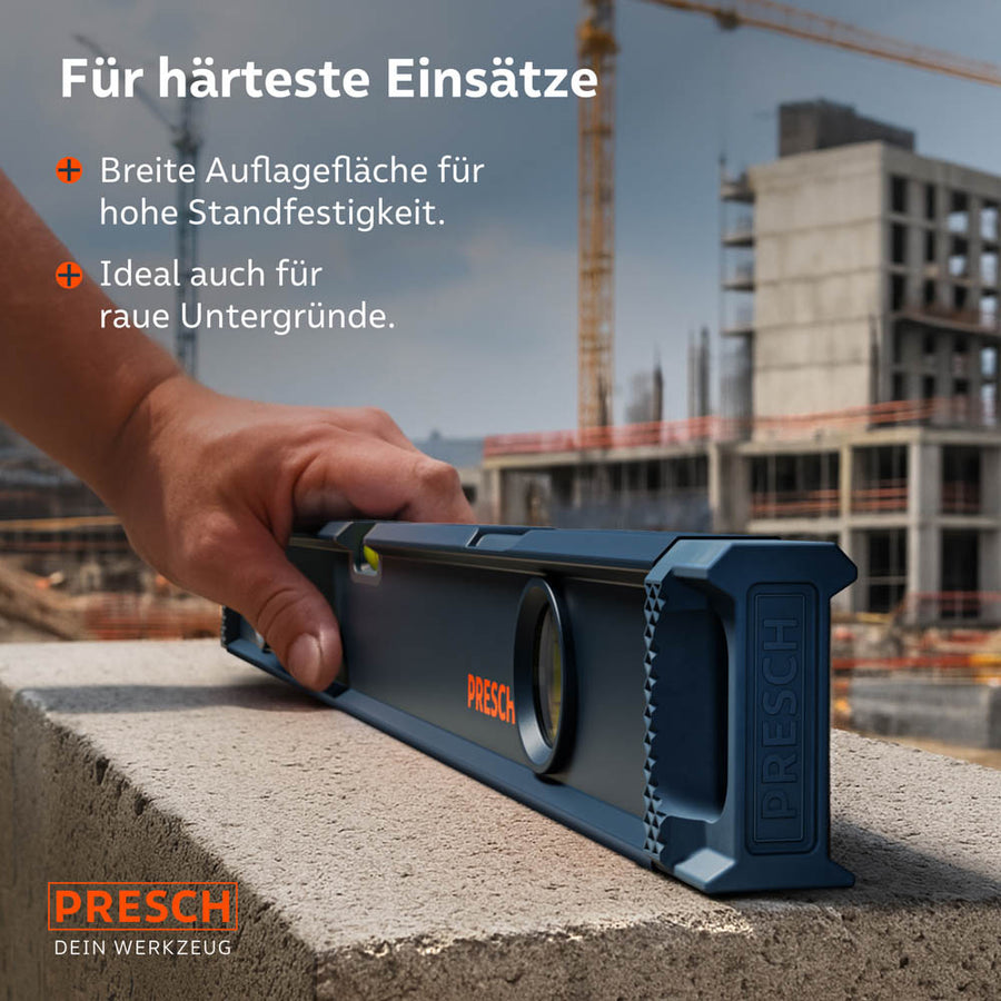 Die Wasserwaage wird auf einem groben Betonblock auf einer Baustelle geführt; die breite, plangefräste Auflagefläche sorgt für eine sichere Positionierung und exakte Messergebnisse auf rauen Untergründen.