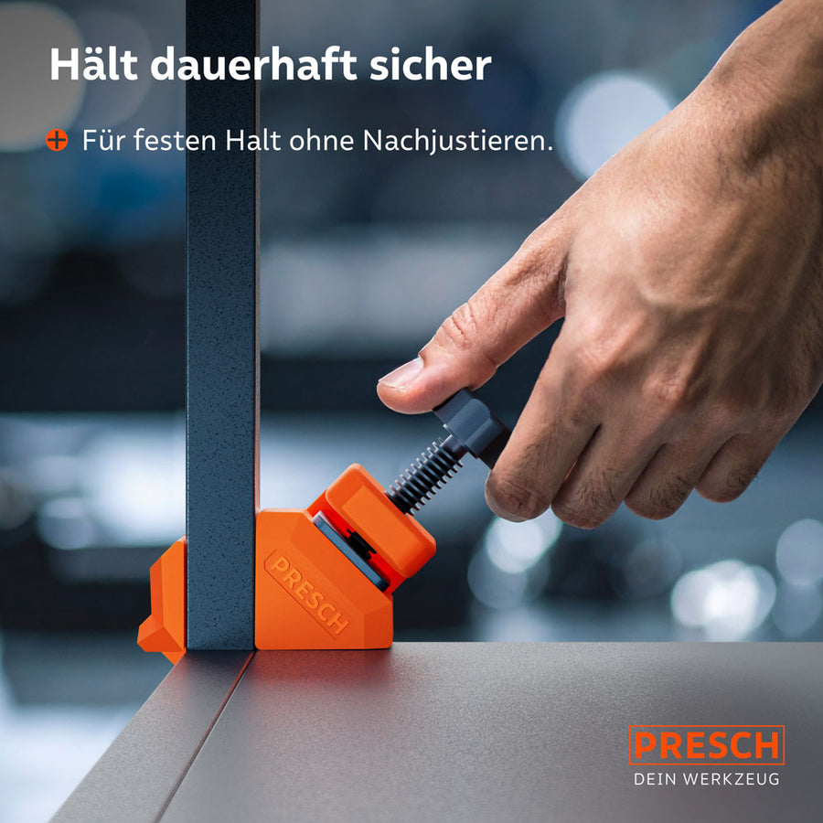 Nahaufnahme der Handhabung: Eine Hand zieht die Gewindeschraube eines orangefarbenen Winkelspanners an, um eine Metallleiste fest mit einer Arbeitsplatte zu verbinden. Bietet festen Halt ohne Nachjustieren.